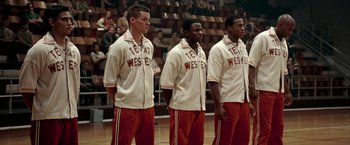Movie still from “Glory Road” (2006), directed by James Gartner – A group of men standing on top of a basketball court; Medium shot, High angle
