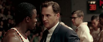 Movie still from “Glory Road” (2006), directed by James Gartner – A man wearing a suit and tie standing next to another man; Close Up shot, Over the shoulder angle