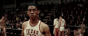 Movie still from “Glory Road” (2006), directed by James Gartner – A young man in a white and red basketball uniform stands in front of an audience; Close Up shot, Over the shoulder angle