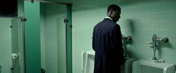 Movie still from “Glory Road” (2006), directed by James Gartner – A man standing in a bathroom next to a urinal; Medium shot, Over the shoulder angle
