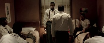 Movie still from “Glory Road” (2006), directed by James Gartner – A man in white shirt and tie looking in the mirror; Medium shot, Over the shoulder angle