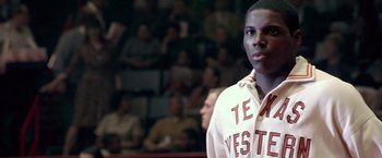 Movie still from “Glory Road” (2006), directed by James Gartner – A man in a white hoodie standing in front of a group of people; Close Up shot, Over the shoulder angle
