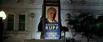 Movie still from “Glory Road” (2006), directed by James Gartner – A large banner hanging in front of a white building; Wide shot, Low angle