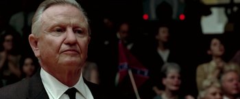 Movie still from “Glory Road” (2006), directed by James Gartner – An older man in a suit and tie holding a confederate flag; Close Up shot, Over the shoulder angle