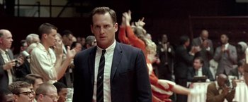 Movie still from “Glory Road” (2006), directed by James Gartner – A man in a suit and tie standing in front of a group of people; Close Up shot, Over the shoulder angle