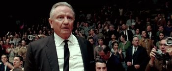 Movie still from “Glory Road” (2006), directed by James Gartner – An older man in a suit and tie in front of an audience; Close Up shot, Low angle