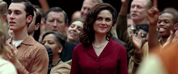 Movie still from “Glory Road” (2006), directed by James Gartner – A woman in a red dress standing in front of a group of people; Close Up shot, Over the shoulder angle