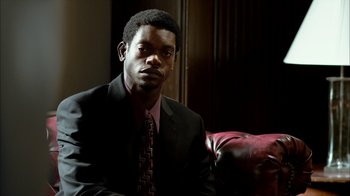 A man wearing a suit and tie sitting in a chair