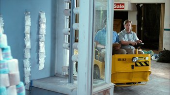 Movie still from “Tim and Eric's Billion Dollar Movie” (2012), directed by Eric Wareheim – Two men are sitting on a forklift in front of a store window; Wide shot, Over the shoulder angle