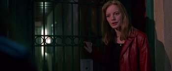 Movie still from “Go” (1999), directed by Doug Liman – A woman standing in front of a metal gate; Medium shot, Low angle