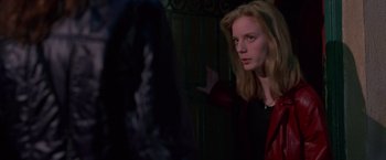 Movie still from “Go” (1999), directed by Doug Liman – A woman in a red jacket looking at a person in a black robe; Medium shot, Over the shoulder angle