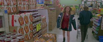 Movie still from “Go” (1999), directed by Doug Liman – A woman walking through a store filled with lots of food; Medium shot, High angle