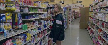 Movie still from “Go” (1999), directed by Doug Liman – A woman is standing in a grocery store looking at products; Medium shot, High angle