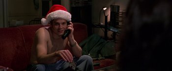 Movie still from “Go” (1999), directed by Doug Liman – A man sitting on a couch talking on a cell phone; Close Up shot, High angle