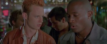 Movie still from “Go” (1999), directed by Doug Liman – A group of men standing next to each other in a room; Close Up shot, Over the shoulder angle