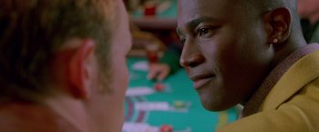 Movie still from “Go” (1999), directed by Doug Liman – A man looking at another man in front of a table; Close Up shot, Over the shoulder angle