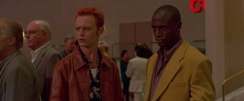 Movie still from “Go” (1999), directed by Doug Liman – A couple of men standing next to each other; Medium shot, Low angle