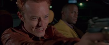 Movie still from “Go” (1999), directed by Doug Liman – A man sitting next to another man in a car; Close Up shot, Low angle