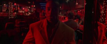 Movie still from “Go” (1999), directed by Doug Liman – A man wearing a suit and tie in a dark room; Close Up shot, Low angle