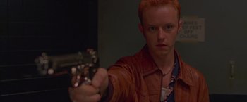 Movie still from “Go” (1999), directed by Doug Liman – A man with red hair is holding a gun; Close Up shot, High angle