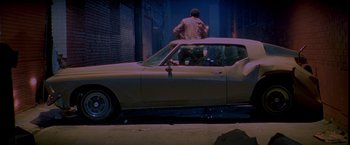 Movie still from “Go” (1999), directed by Doug Liman – A man sitting on the hood of a car; Wide shot, High angle