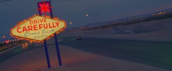 Movie still from “Go” (1999), directed by Doug Liman – A street sign on the side of a road; Extreme Wide shot, Low angle