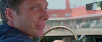 Movie still from “Go” (1999), directed by Doug Liman – A person in a car looking at the camera; Close Up shot, Over the shoulder angle