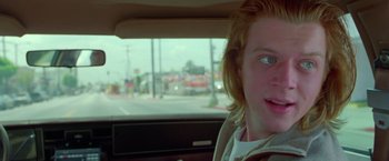 Movie still from “Go” (1999), directed by Doug Liman – A young man sitting in the back seat of a car; Close Up shot, Low angle