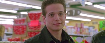 Movie still from “Go” (1999), directed by Doug Liman – A young man in a black jacket is smiling; Close Up shot, Over the shoulder angle