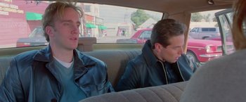 Movie still from “Go” (1999), directed by Doug Liman – Two people sitting in the back seat of a car; Medium shot, Over the shoulder angle