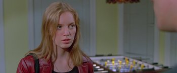 Movie still from “Go” (1999), directed by Doug Liman – A woman with long red hair wearing a black shirt and a red jacket; Close Up shot, Over the shoulder angle