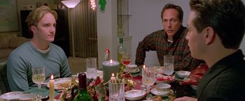 Movie still from “Go” (1999), directed by Doug Liman – A man sitting at a dinner table with candles lit; Medium shot, High angle