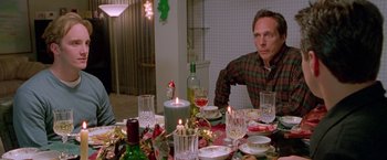 Movie still from “Go” (1999), directed by Doug Liman – A man sitting at a dinner table with candles; Medium shot, High angle