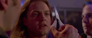 Movie still from “Go” (1999), directed by Doug Liman – A man holding a pair of scissors up to his face; Close Up shot, Low angle