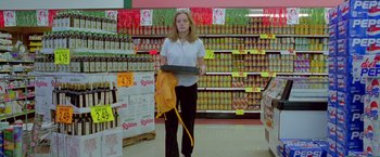 Movie still from “Go” (1999), directed by Doug Liman – A woman is holding a tray in a store; Wide shot, Low angle