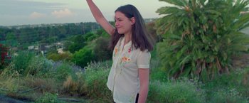 Movie still from “Go” (1999), directed by Doug Liman – A young girl is standing in a field waving; Medium shot, Low angle