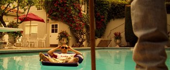Movie still from “Goal! The Dream Begins” (2005), directed by Michael Winterbottom – A man sitting on a raft in a swimming pool; Wide shot, High angle