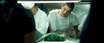 Movie still from “Goal! The Dream Begins” (2005), directed by Michael Winterbottom – A man in a white shirt and white apron looking at a bunch of green beans on a counter; Close Up shot, Over the shoulder angle