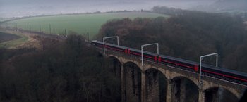Movie still from “Goal! The Dream Begins” (2005), directed by Michael Winterbottom – A train traveling over a bridge near a lush green field; Extreme Wide shot, High angle