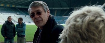Movie still from “Goal! The Dream Begins” (2005), directed by Michael Winterbottom – A person wearing sunglasses and a jacket; Close Up shot, Over the shoulder angle
