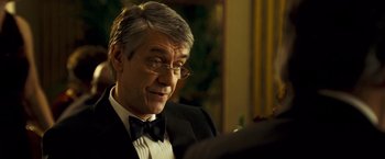 Movie still from “Goal! The Dream Begins” (2005), directed by Michael Winterbottom – An older man in a suit and bow tie; Close Up shot, Over the shoulder angle