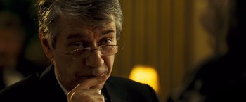 Movie still from “Goal! The Dream Begins” (2005), directed by Michael Winterbottom – An older man wearing glasses and a black suit; Close Up shot, Over the shoulder angle