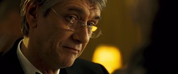 Movie still from “Goal! The Dream Begins” (2005), directed by Michael Winterbottom – An older man wearing glasses looking at the camera; Close Up shot, Over the shoulder angle