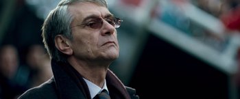Movie still from “Goal! The Dream Begins” (2005), directed by Michael Winterbottom – An older man wearing a suit and sunglasses; Close Up shot, Low angle