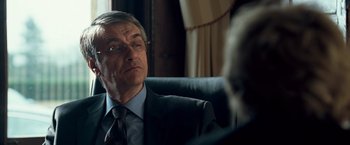 Movie still from “Goal! The Dream Begins” (2005), directed by Michael Winterbottom – An older man wearing a suit and tie sitting in a chair; Close Up shot, Over the shoulder angle
