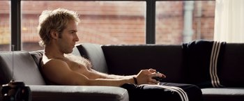 Movie still from “Goal! The Dream Begins” (2005), directed by Michael Winterbottom – A man sitting on a couch playing a video game; Medium shot, High angle