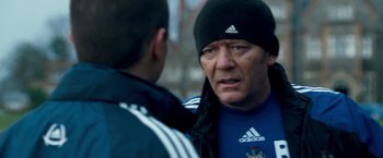 Movie still from “Goal! The Dream Begins” (2005), directed by Michael Winterbottom – A man in a black hat is talking to another man; Close Up shot, Over the shoulder angle