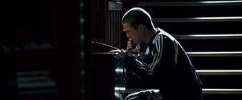 Movie still from “Goal! The Dream Begins” (2005), directed by Michael Winterbottom – A man sitting in front of a window looking down; Medium shot, High angle