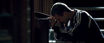Movie still from “Goal! The Dream Begins” (2005), directed by Michael Winterbottom – A man leaning against a desk with his head on his hand; Close Up shot, High angle