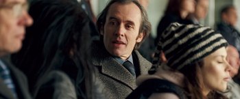 Movie still from “Goal! The Dream Begins” (2005), directed by Michael Winterbottom – A person wearing a suit and tie; Close Up shot, Over the shoulder angle